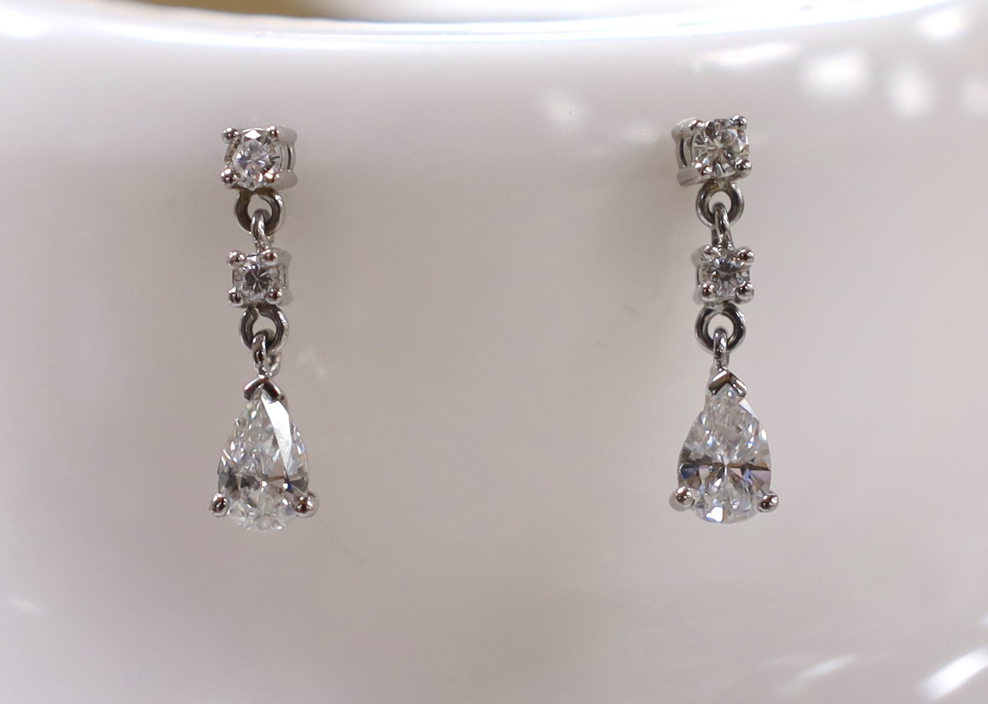 A modern pair of 750 white metal, pear and round cut diamond set drop earrings, 18mm, gross weight 2.8 grams